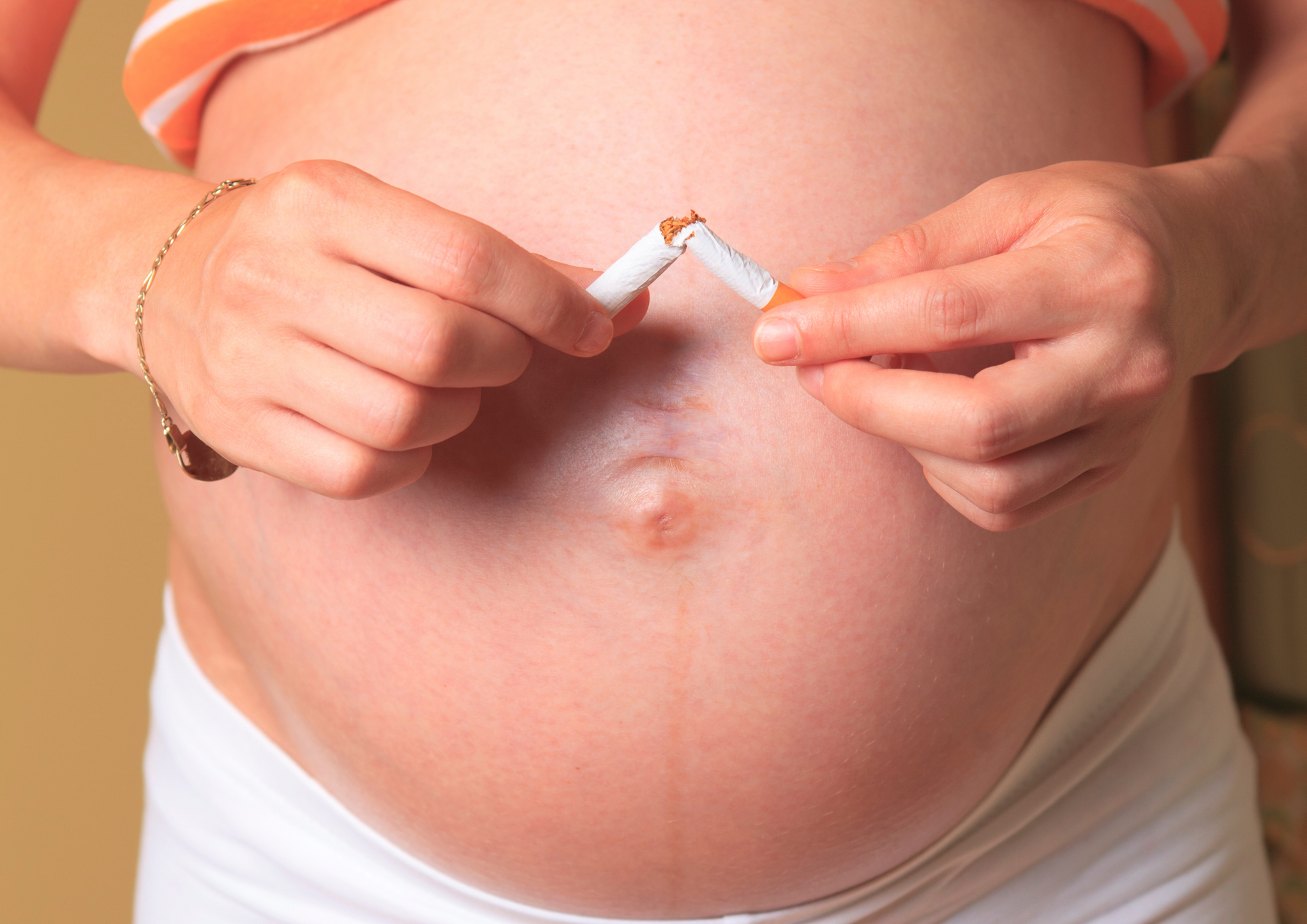 Pregnant lady holding a  cigarette.