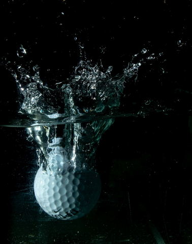 A white golf ball sinking in a body of water