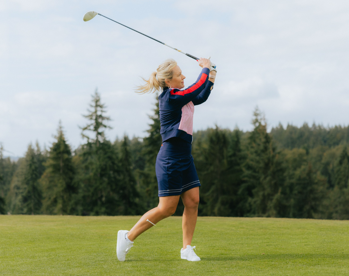 A woman swinging a golf club on the course