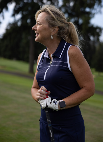 A golfer wearing a dark blue outfit, holding a golf club on the course