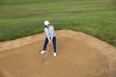 A woman wearing pants and a long-sleeved shirt on a golf course