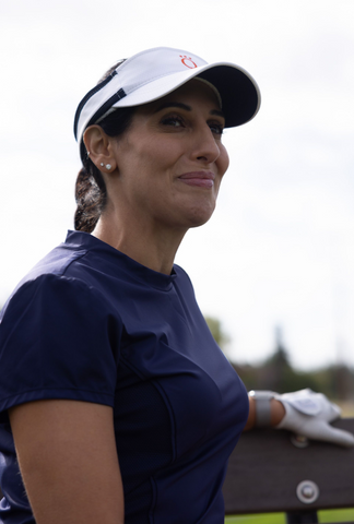 A woman wearing a blue shirt and a white visor