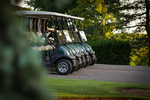A row of golf carts lined up on pavement