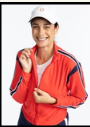 Woman smiling zipping up red golf jacket.