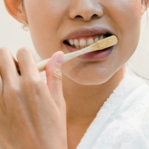 Face of a woman brushing her teeth with a bamboo toothbrush