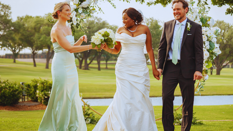 Asymmetrical wedding gown on a beautiful bride with her groom and maid of honor.