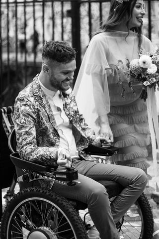 beautiful custom floral suit on a handsome groom with his bride