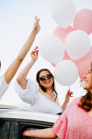 happy bride holding balloons smiling with sunglasses