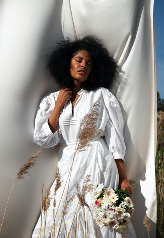 Beautiful woman with wind blowing around her hair and cotton wedding dress holding a bouquet of flowers in the sunshine. Here we dive into wedding trends of the future.