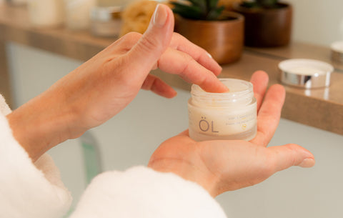 Femme qui prend crème visage éclat ÖL cosmétiques dans le pot