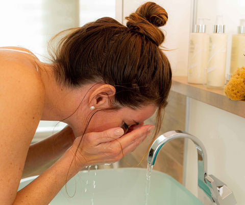 Femme qui nettoie sa peau avec le lait nettoyant pour le visage ÖL cosmétiques