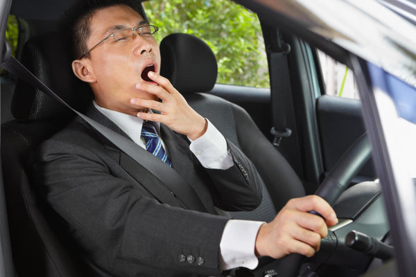 A man yawns behind the wheel and is too tired to drive