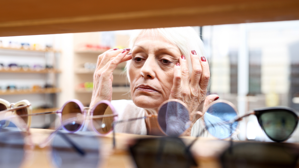 Older woman looking at her eyes in a glasses store.