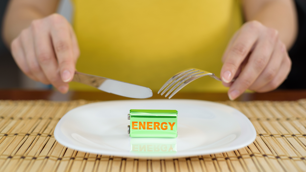 A woman jokingly about to cut a battery that says "Energy," signaling that the food we eat gives us energy.