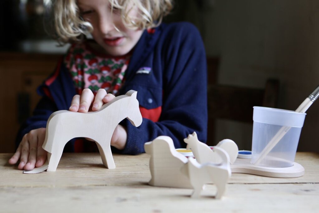 Child sanding the wooden horse figure blank from the Ostheimer Creative Painting Set