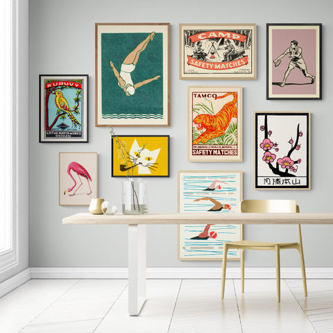 A wall of bright art prints in a sunny white room