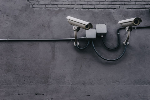 two grey CCTV cameras with visible cables