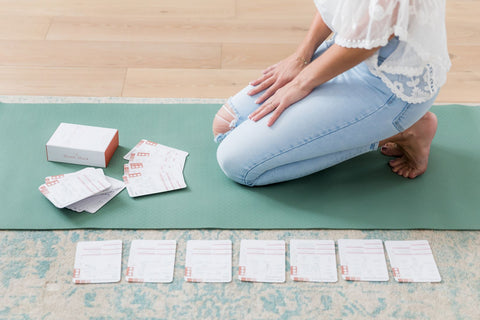 Yogini kneeling on her yoga mat with yoga cards