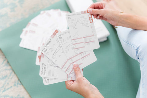 Yogini holding yoga cards and choosing an individual card to use in her practice