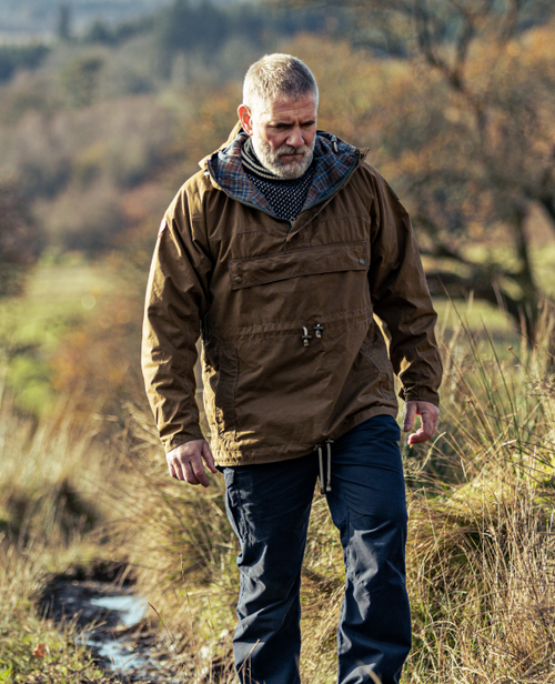 Man walking in grass wearing a brown Skarbek smock