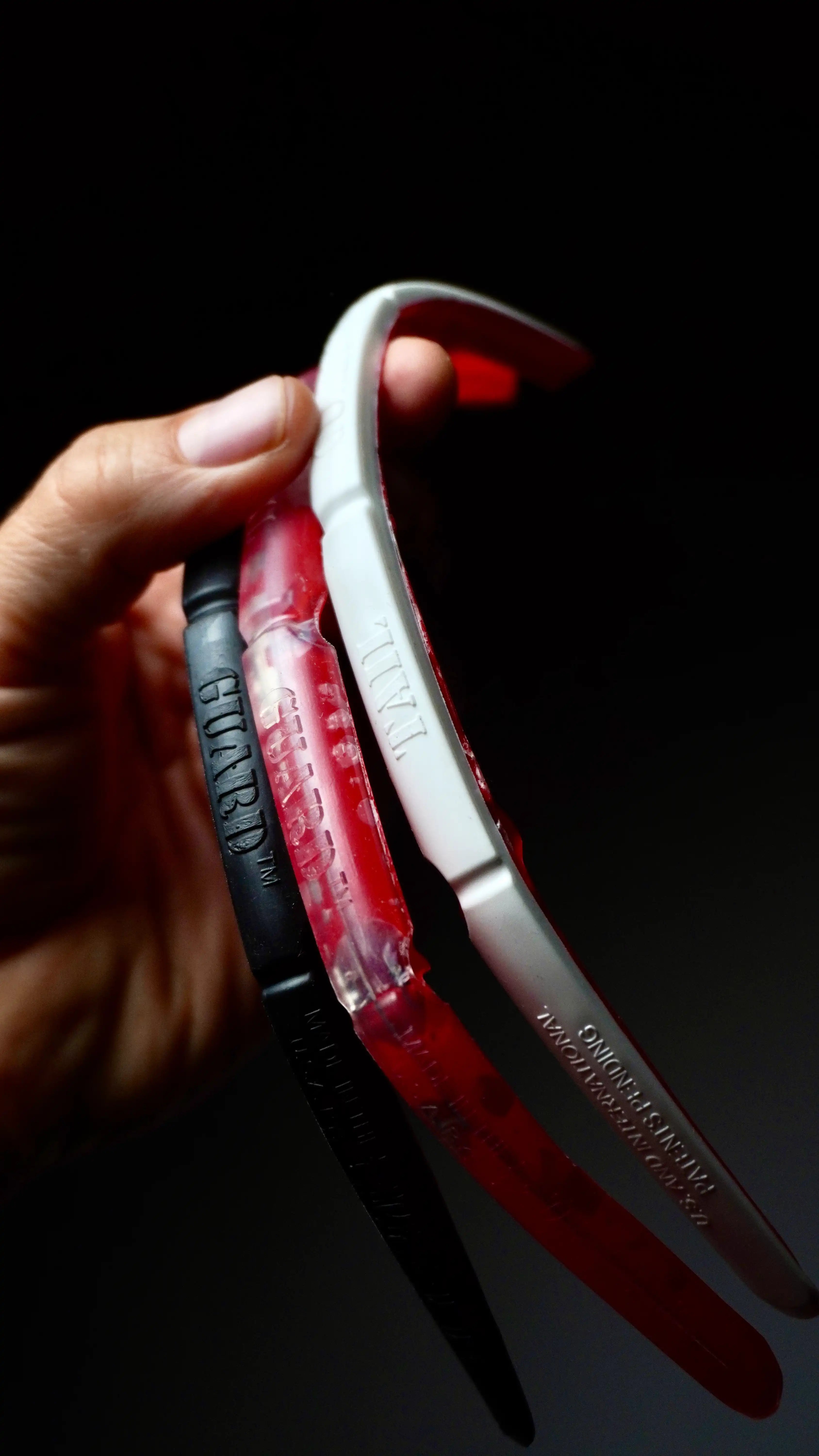 Close-up of the SurfCo Hawaii Tail Guard in hand – available in black, clear, and white, with a flexible curved design.