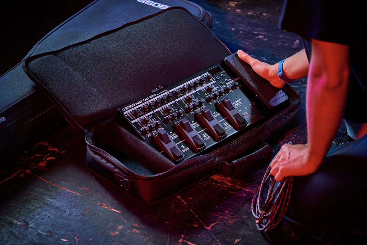 A guitarist on a stage, removing the ME-90 from it's carrying case to set up for a gig.