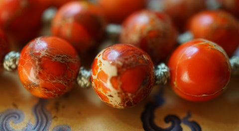 close up view of orange jasper beads with silk green knots between to showcase and protect beads