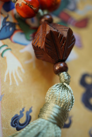 close up view of carved wooden guru and silk green tassel