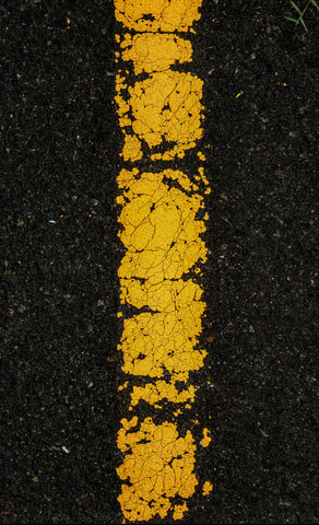 black pavement with painted cracked yellow line