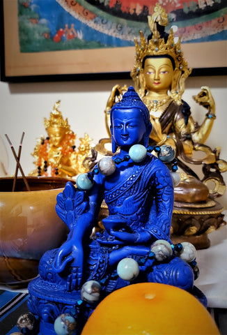 Aqua Terra quarter mala adorning deep blue Medicine Buddha statue on home altar space.