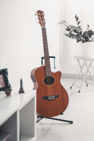 Guitar on stand in room painted white.