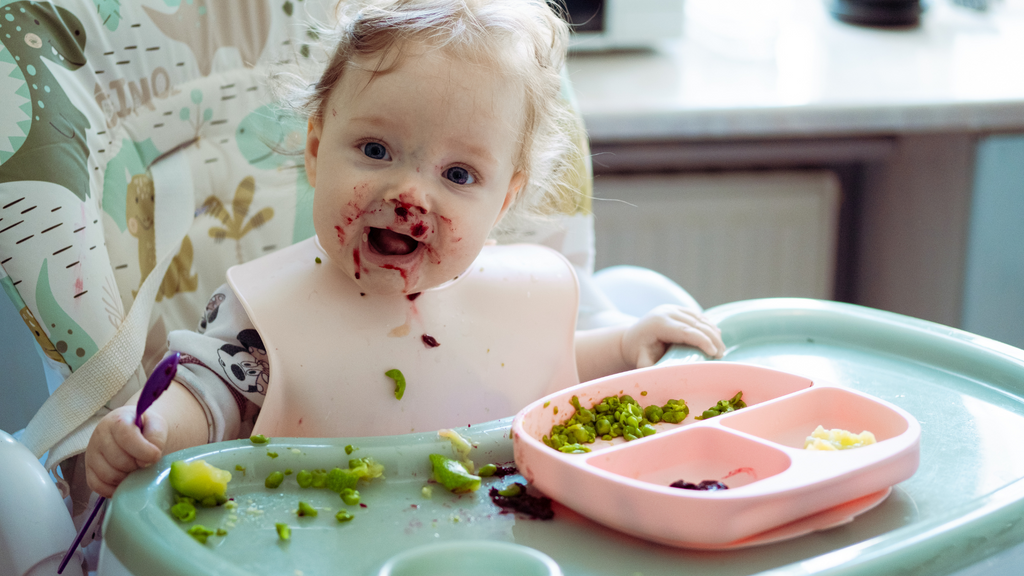 Adorable baby enjoying Baby-Led Weaning and making a delightful mess