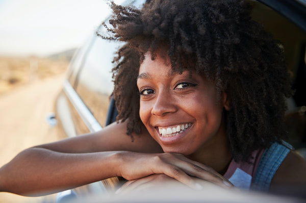 Woman looking out a car window on a road trip (Photo via Envato Elements)