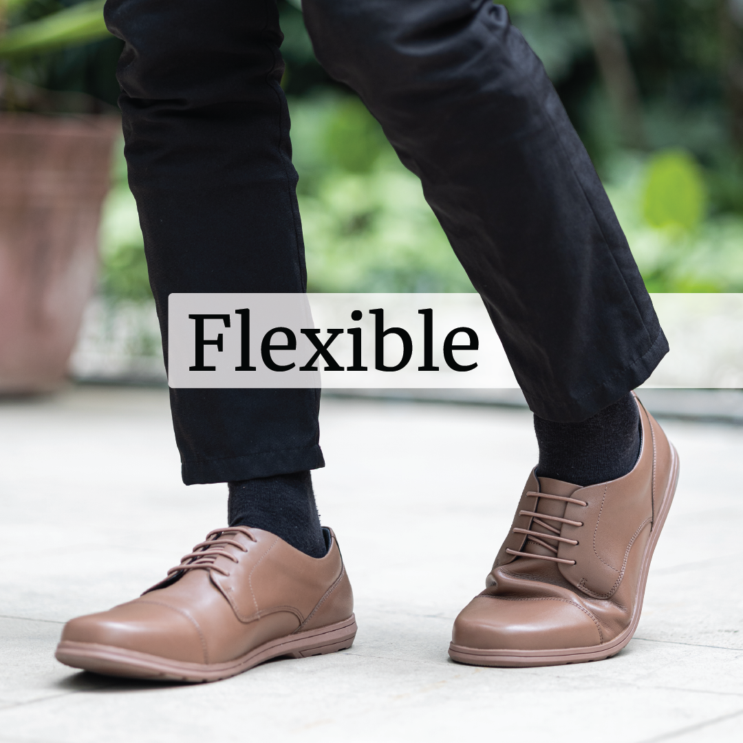 Close-up of a person's feet wearing brown shoes with the word 'Flexible' overlaid.