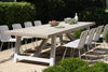 Dining table set featuring large teak and aluminium table with white dining side chairs