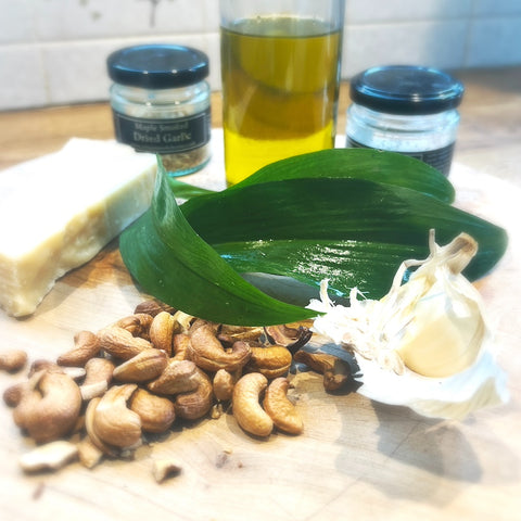 A board containing the ingredients for smoked pesto recipe, including smoked olive oil, nuts, Parmesan & wild garlic