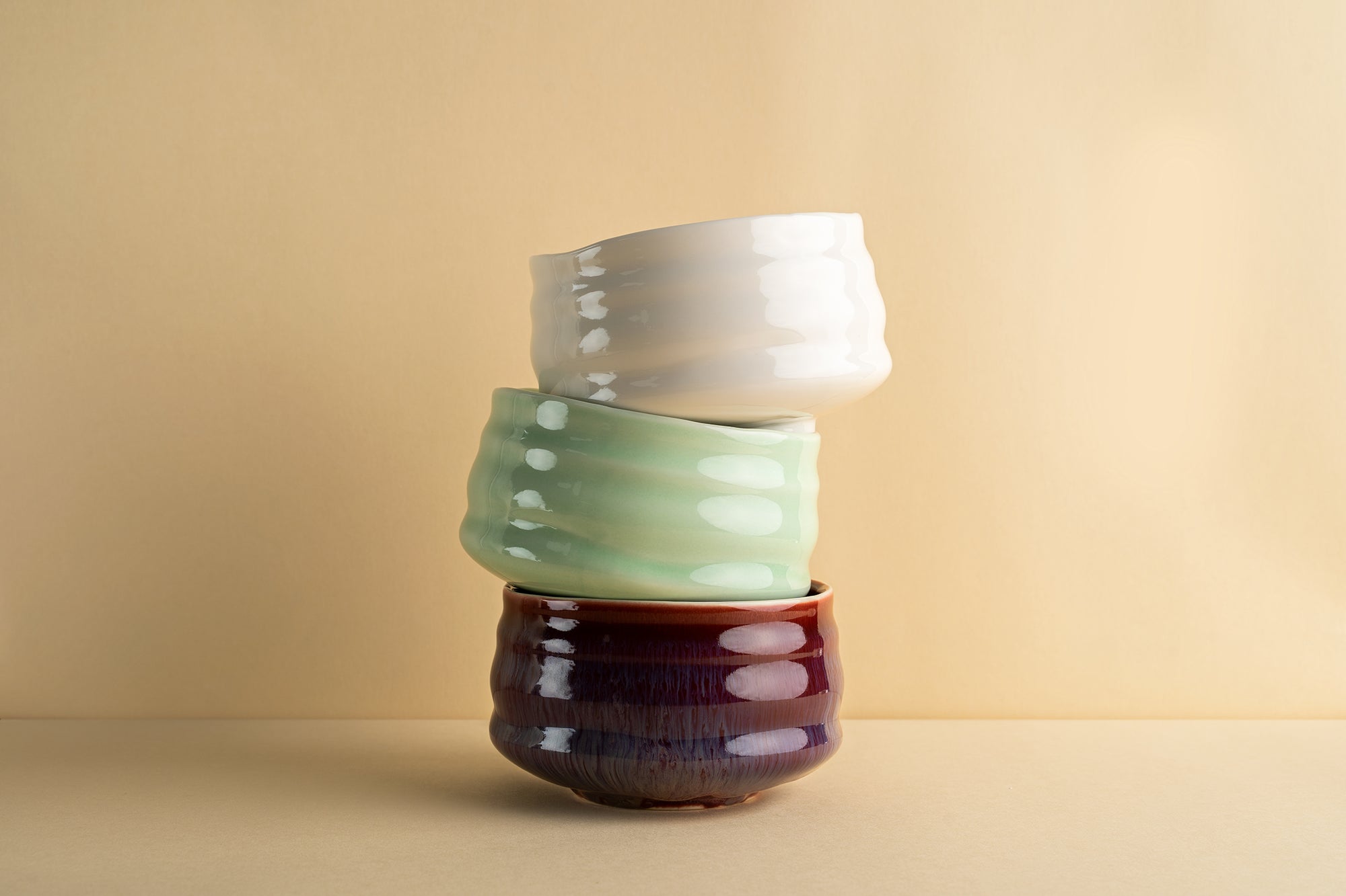 A stack of three bowls that are red, green, and white.
