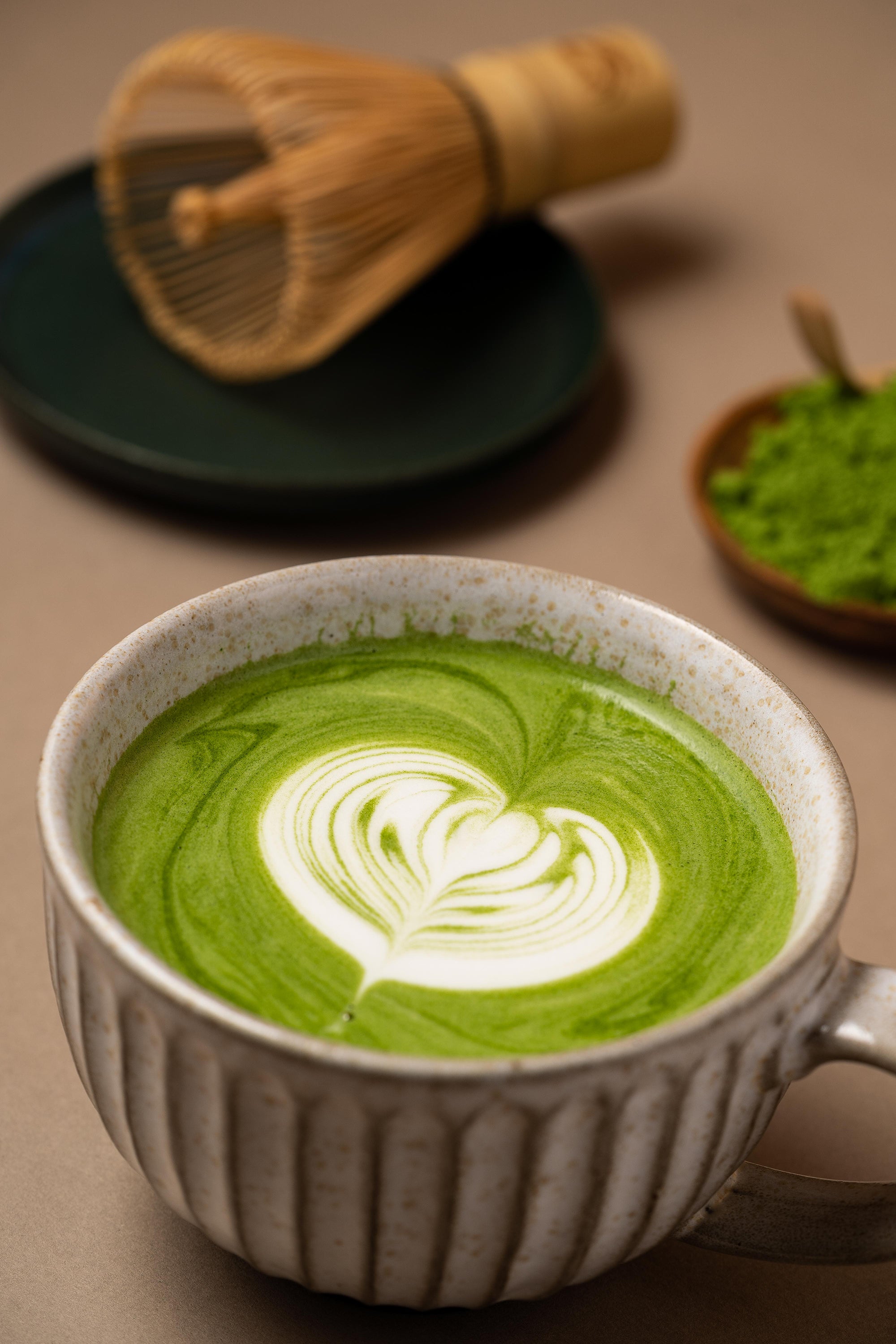 Matcha latte with a whisk in the background