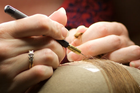 Close-up of hair strands being sewn into a cap