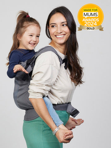 Woman carries toddler on her back in the Izmi Breeze Toddler Carrier