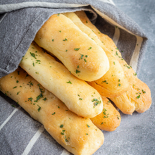 gluten-free breadsticks are gathered in a decorative towel. They are brushed in butter and sprinkled with parsley, and look like Olive Garden breadsticks.