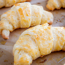 gluten-free croissants are shown on a weathered baking sheet. They are flaky and golden brown.