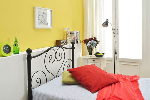赤いクッションと絵画が飾ってある寝室