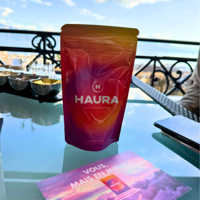 A HAURA beverage container on a table with a scenic backdrop.