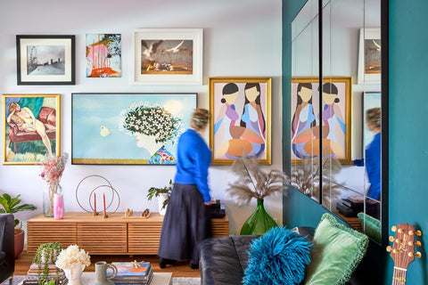Arlene Austin in blue jumper with Art gallery style feature wall in living room