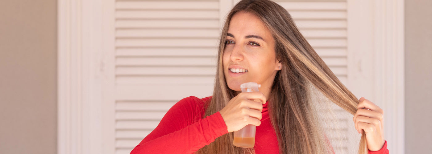 Woman with clip in hair extensions using heat protectant spray