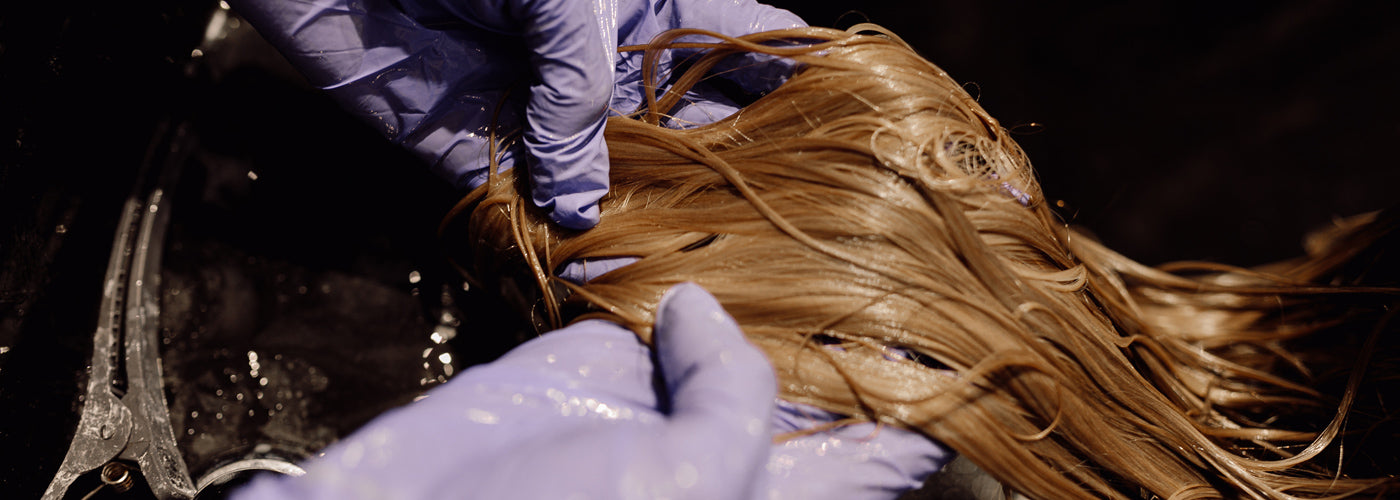 Woman washing clip-in hair extensions with lukewarm water