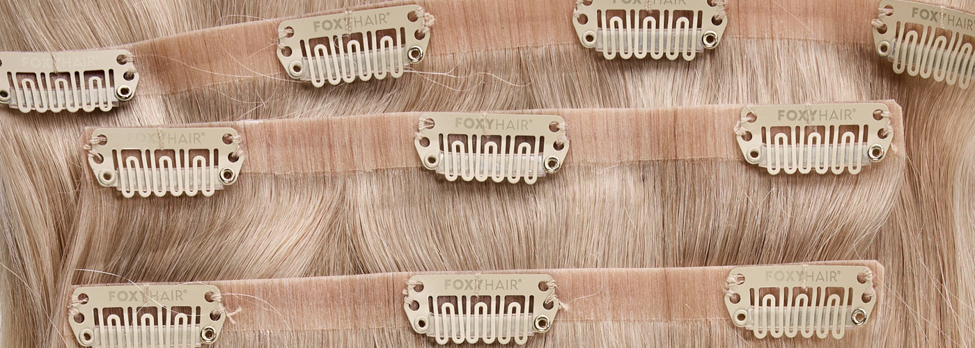 Various types of clip-in hair extensions are displayed on a table