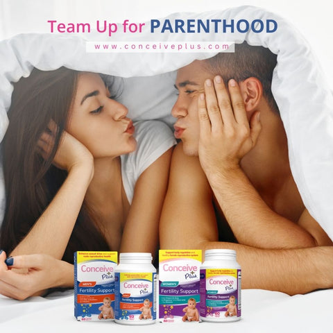 Una pareja feliz mirándose bajo una manta y haciendo pucheros, con un suplemento de fertilidad para mujeres y un suplemento para hombres Conceive Plus colocado frente a ellos.
