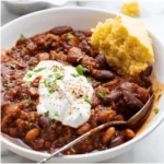 Chili topped with sour cream and cornbread.